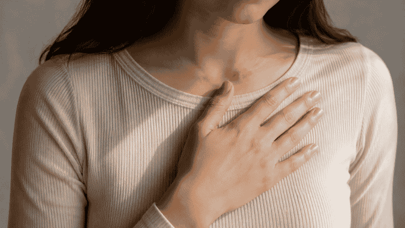 A close-up of a person's hand gently placed over their chest, representing the connection between poor sleep and cardiovascular health risks