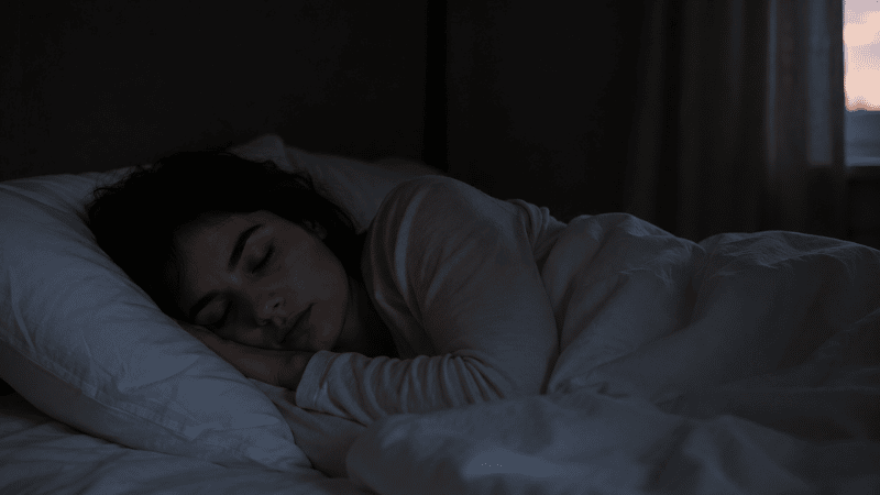 A person sleeping deeply and undisturbed through the night in a dark calm bedroom, representing finally breaking the 3am waking pattern and sleeping through to morning