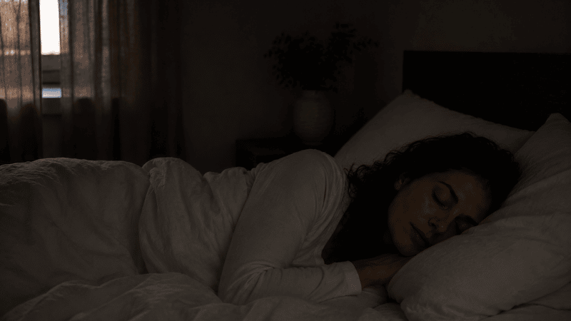 A person sleeping completely undisturbed through the night in a dark peaceful bedroom, faint early morning light barely visible, representing the outcome of sleeping through the night with no waking