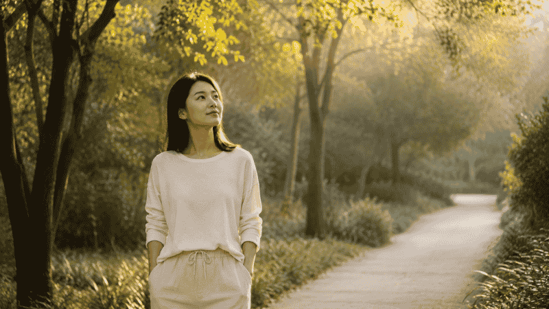 A person walking calmly outdoors in morning light, representing daytime physical movement as a way to regulate cortisol and reduce the anxiety that disrupts sleep
