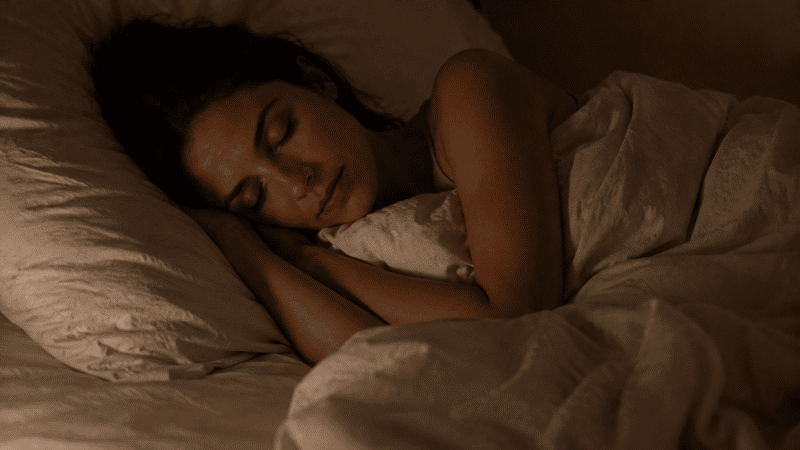 A person sleeping peacefully and deeply in a dark calm bedroom, representing the quiet rest that follows when nighttime anxiety has been understood and addressed
