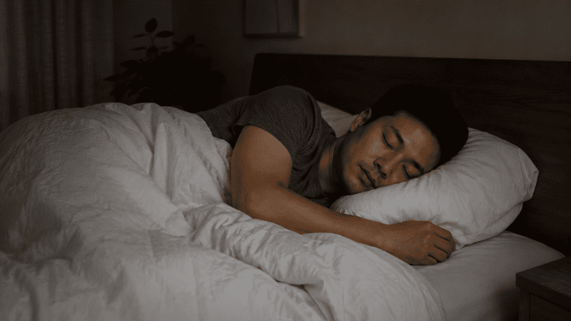 A person sleeping deeply and peacefully in a cool dark bedroom, representing the cardiovascular protection provided by consistent restorative sleep and a healthy nocturnal blood pressure dip