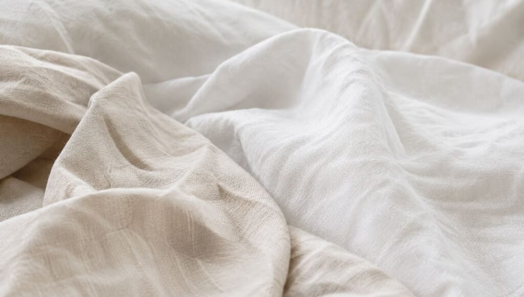 Close-up of soft breathable linen bedding in natural cream tones, representing moisture-wicking bedding material that helps reduce the impact of night sweats